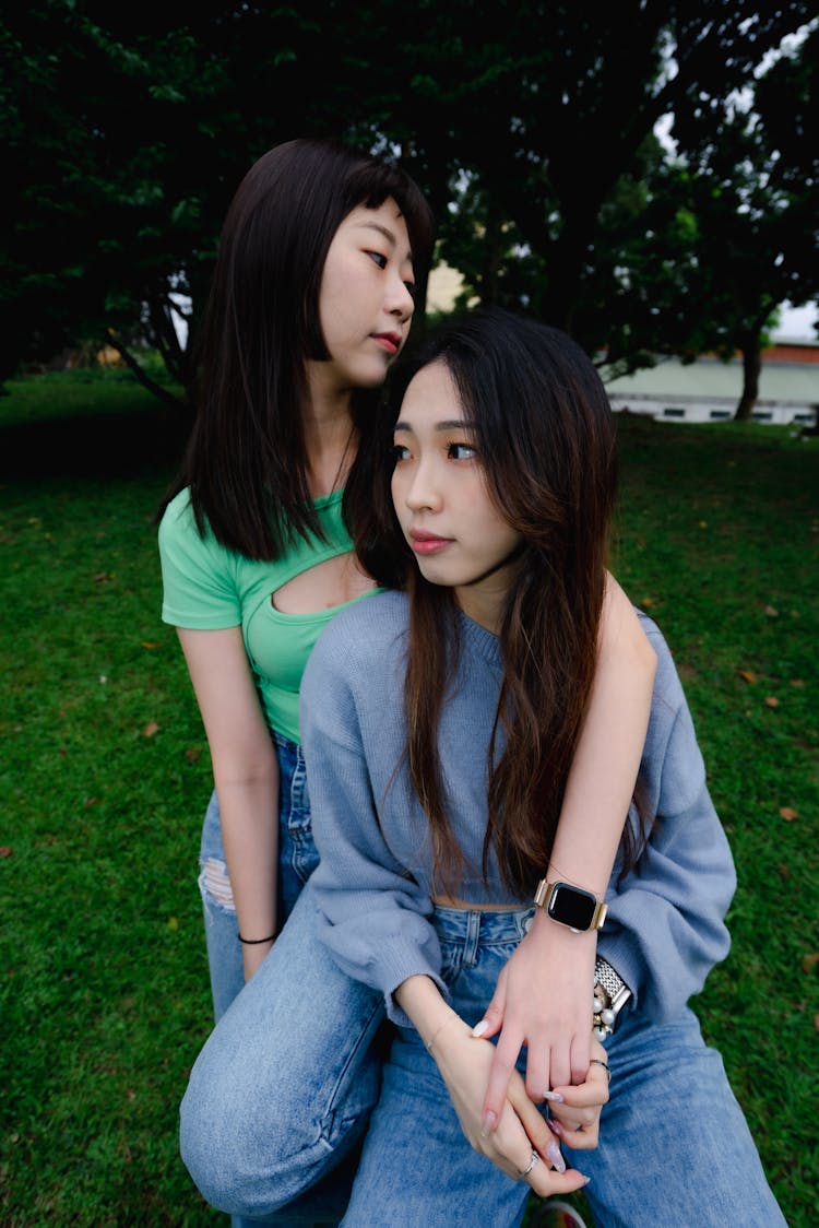 Two Girls In A Park Sitting Together 