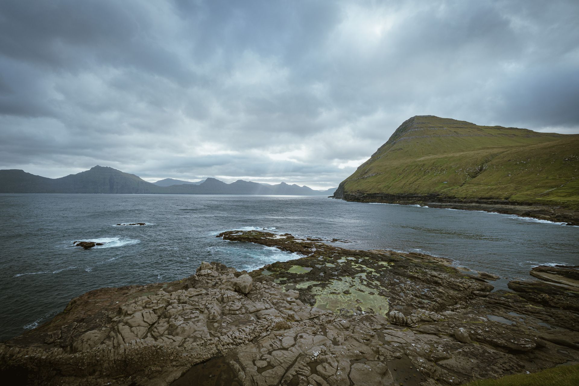 Dramatic seascape with rocky shores and cloudy sky, epitomizing rugged coastal beauty.