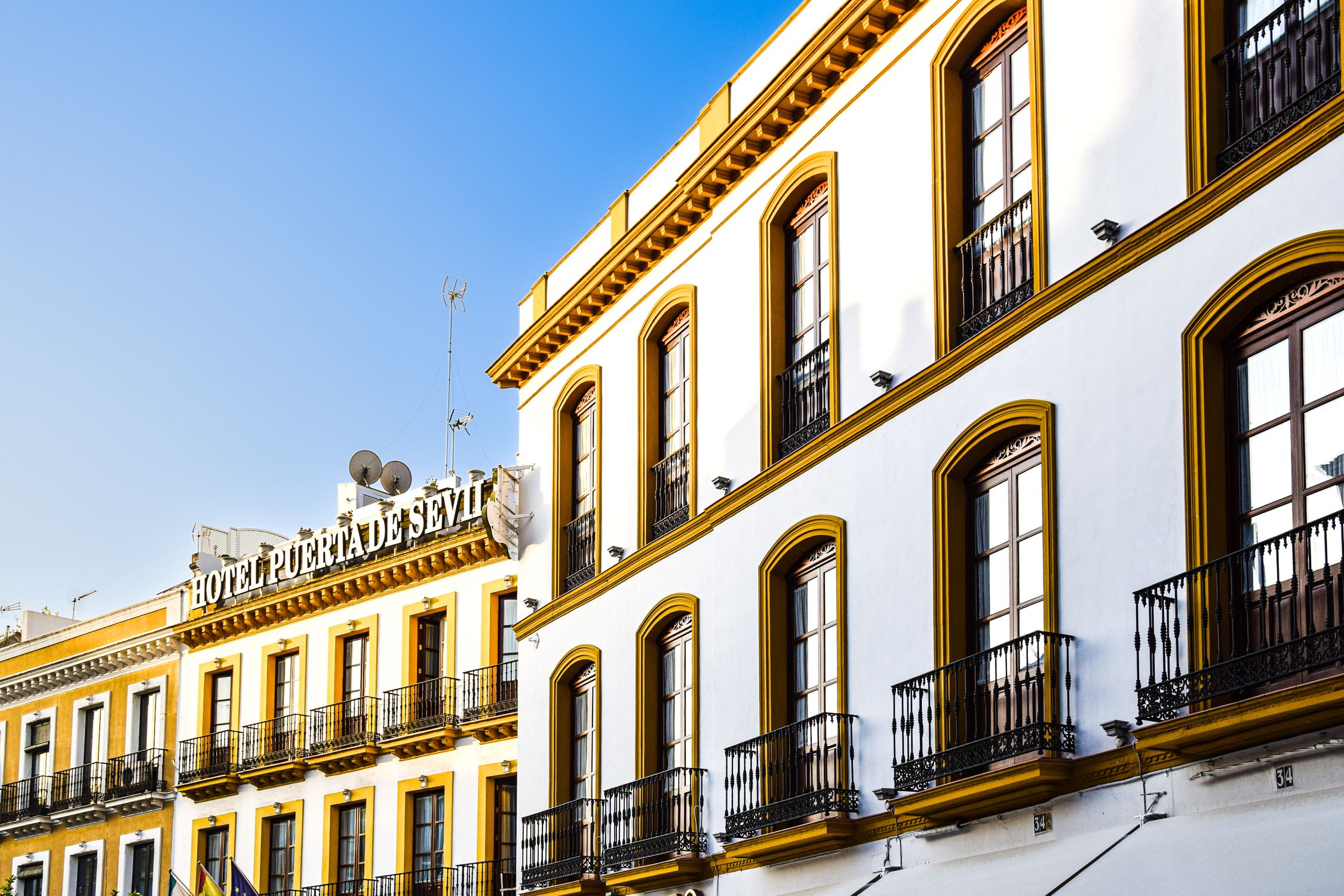 Elegant architectural facade of a Seville hotel bathed in sunlight, capturing its iconic charm