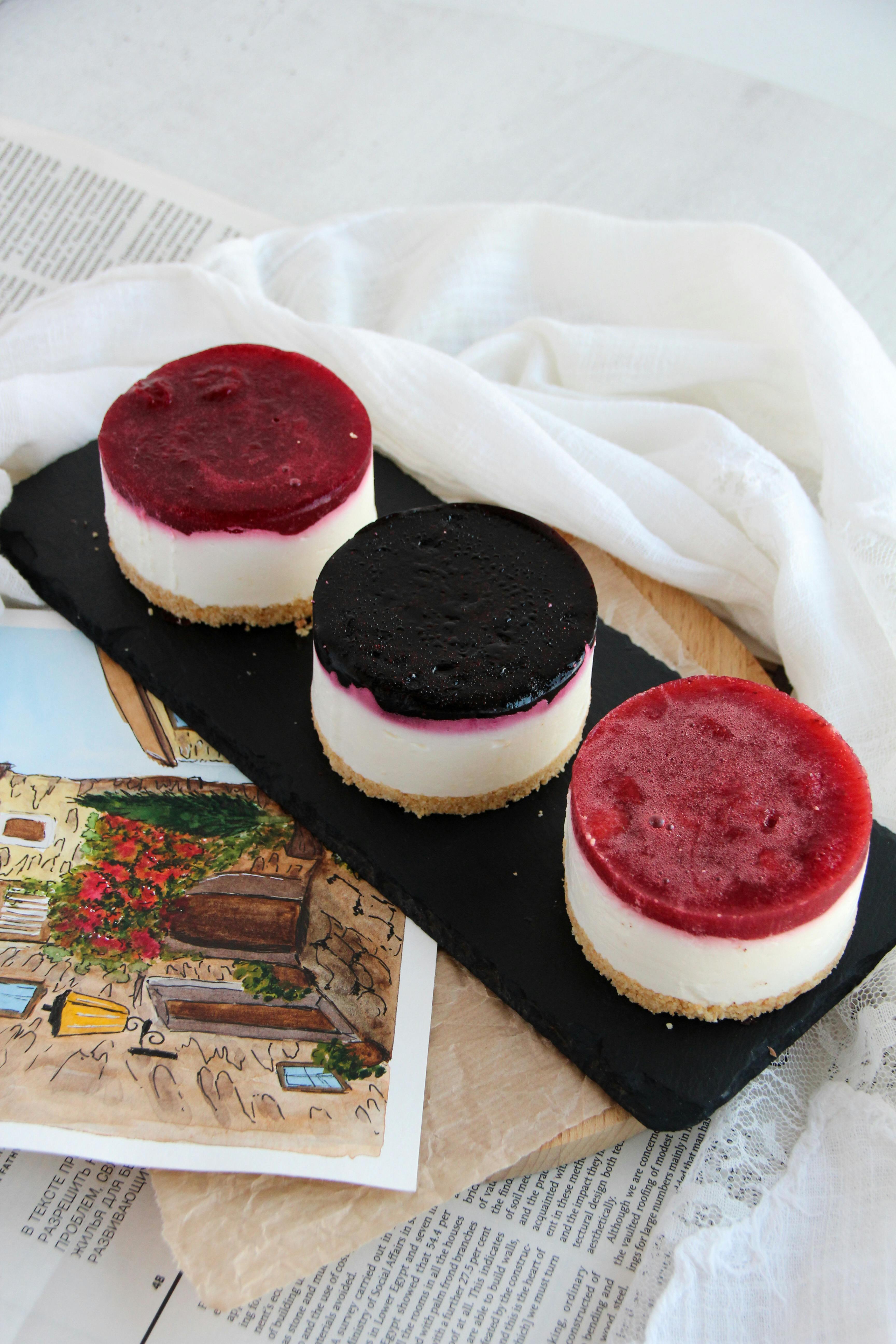 Three mini cheesecakes topped with berries on a slate board, perfect for desserts.
