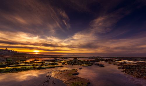 Free Stunning sunset over rocky coastline with vibrant sky colors and tranquil sea reflections. Stock Photo