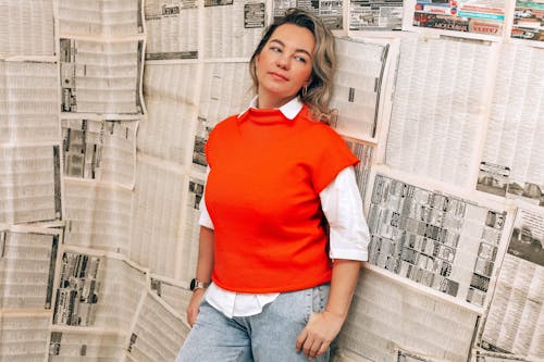 A Blonde Woman Posing in front of Newspaper Background