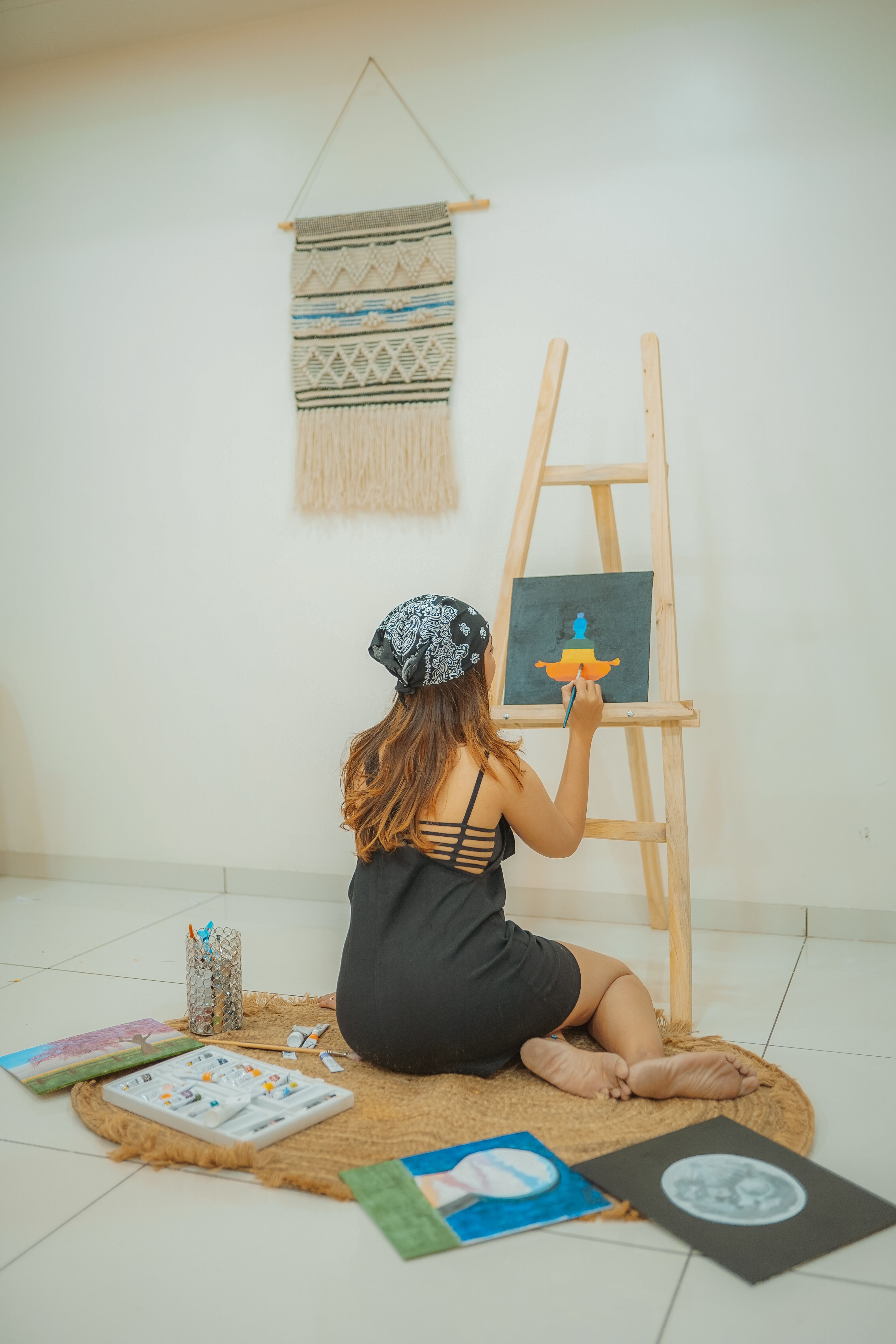 Young woman painting on an easel indoors, expressing creativity and skill.