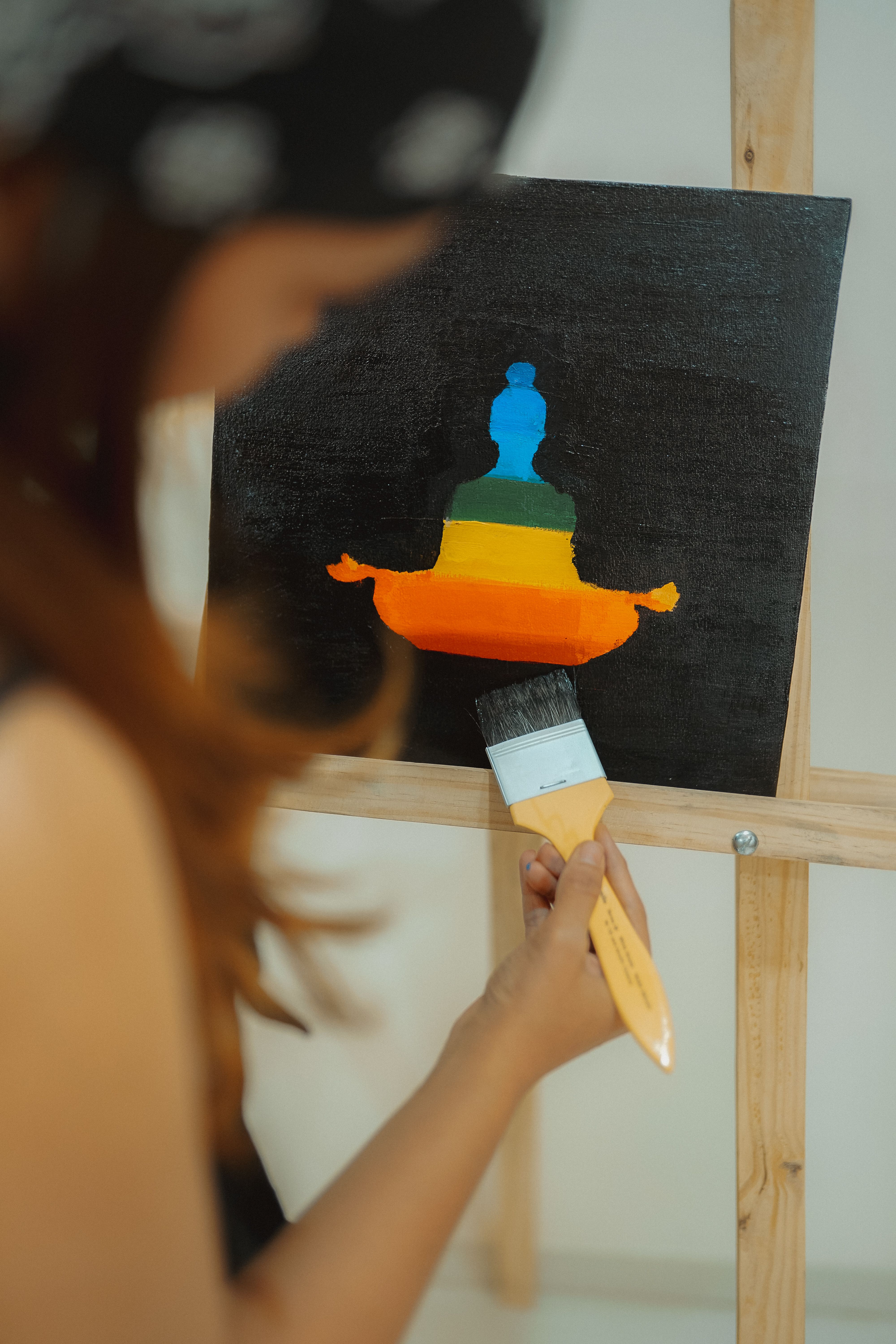 A woman artist using a paintbrush to create a vibrant meditative painting on canvas.