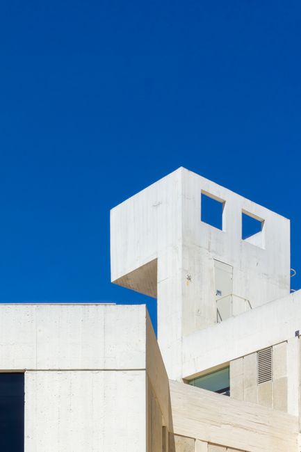 Close-up of a modern white concrete building against a clear blue sky in Barcelona.