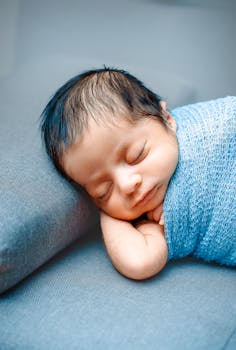 Adorable newborn peacefully sleeping, wrapped in a blue blanket, capturing innocence and tranquility.