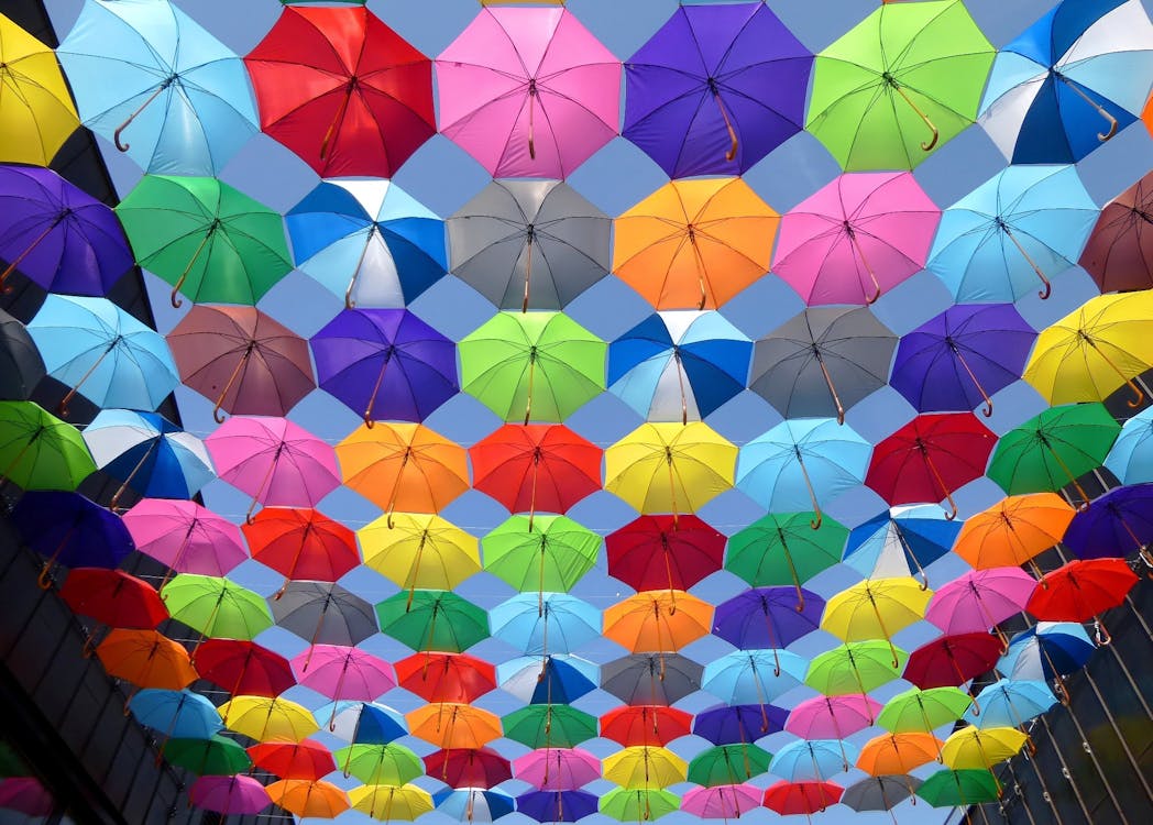 Free Yellow Blue Red Pink Purple Green Multicolored Open Umbrellas Hanging on Strings Under Blue Sky Stock Photo