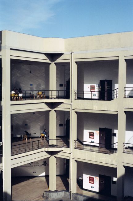 A sunlit urban building with open mezzanines and visible walkways.