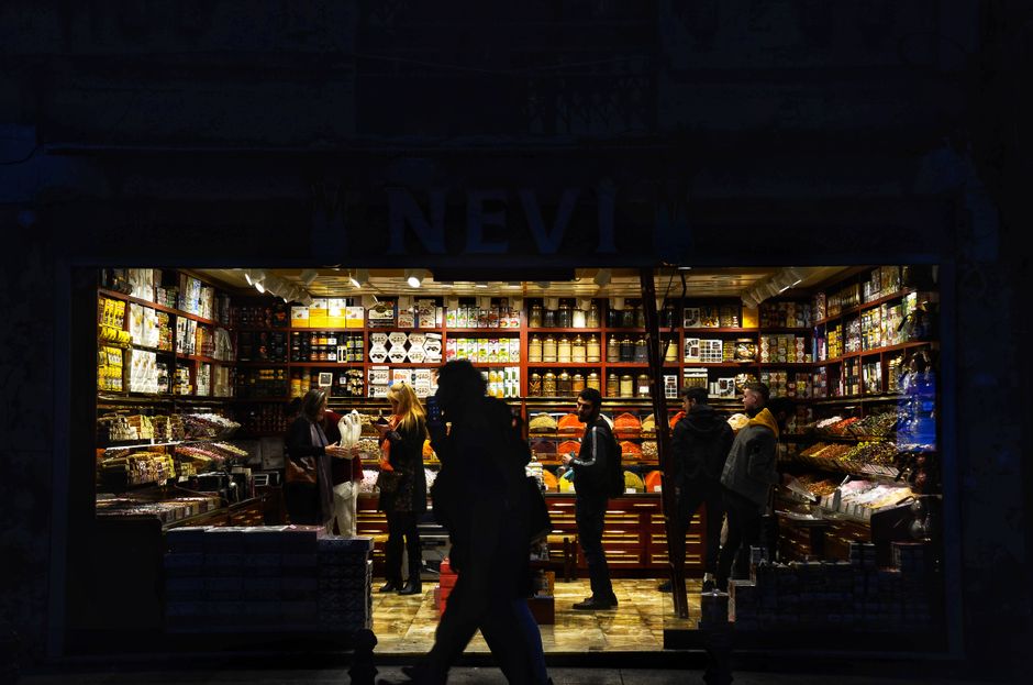 Una vibrante tienda iluminada en la calle llena de personas comprando por la noche.