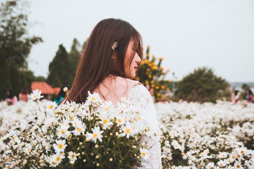 免费 女人站在白色的雏菊花附近 素材图片