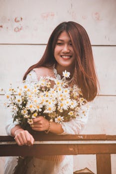 一位年轻女子在温暖的户外愉快地与白雏菊合影