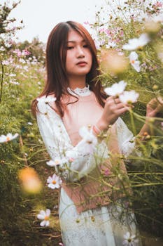 一名穿着时尚连衣裙的年轻女子，被盛开的鲜花包围在户外花园里