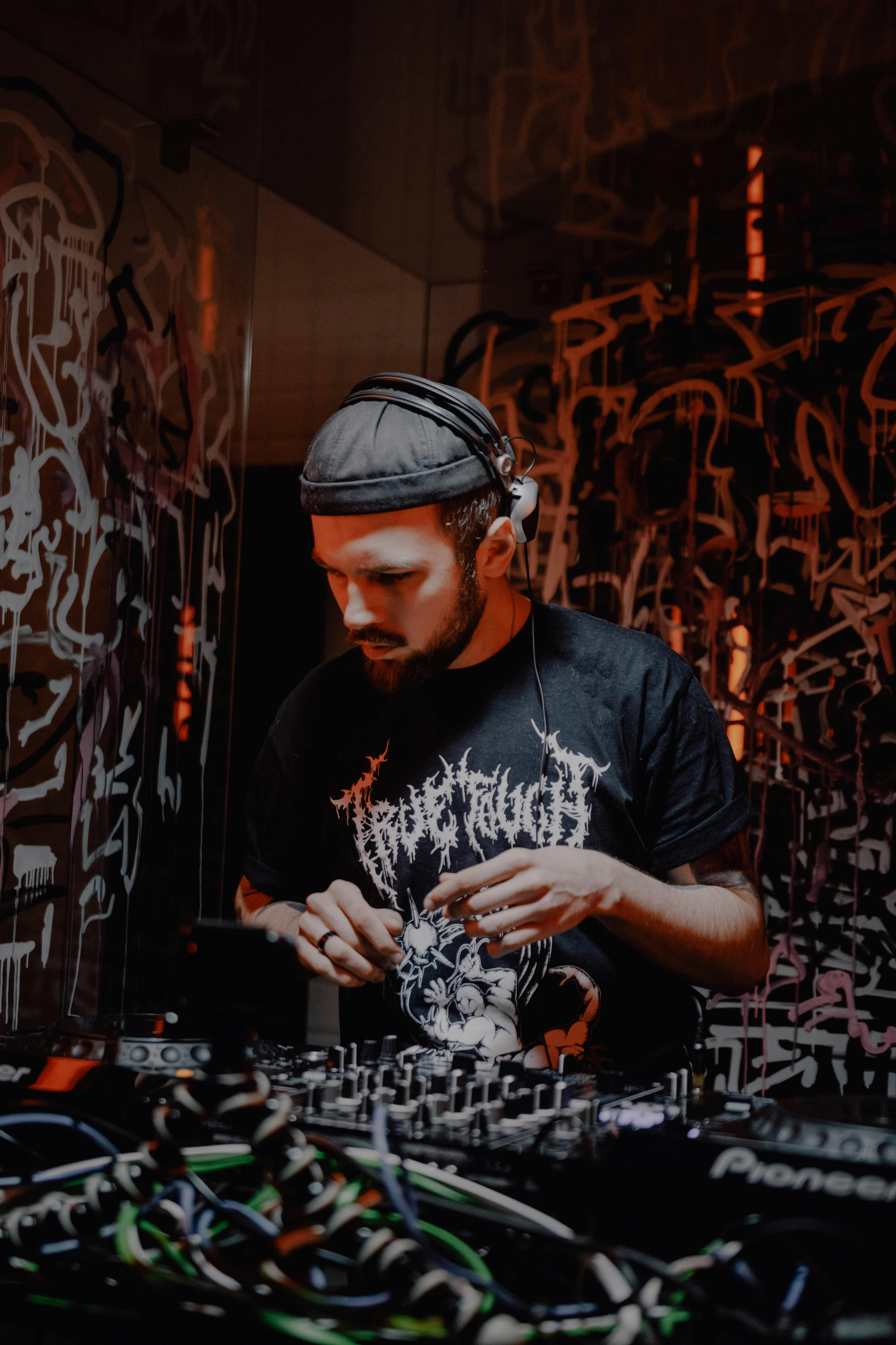 DJ mixes tracks at a vibrant indoor music event in Lviv, Ukraine, surrounded by graffiti.