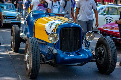 Free Colorful vintage racing car on display at an outdoor car gathering, surrounded by people. Stock Photo