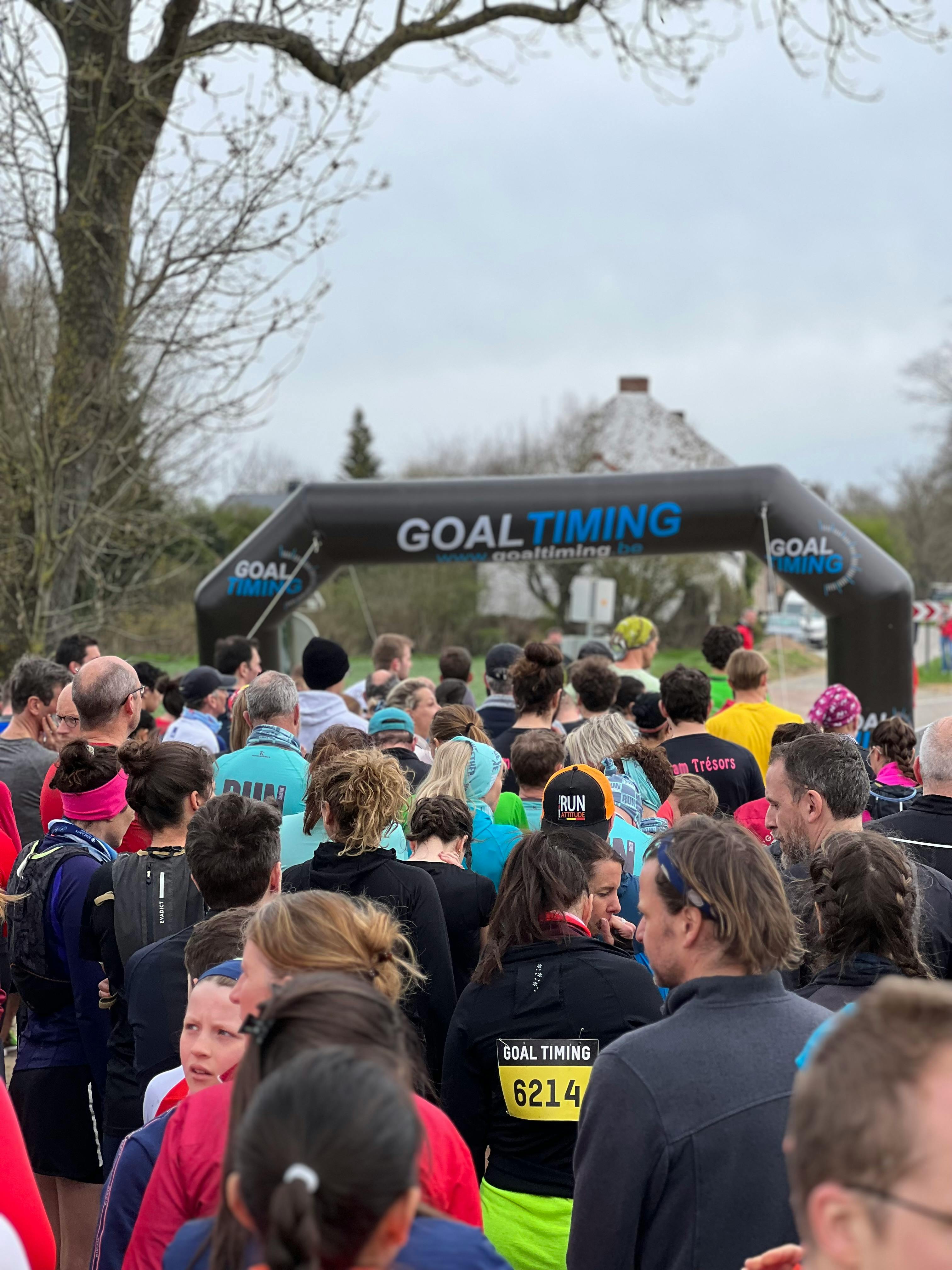 Participants gathered at an outdoor race event under a Goal Timing arch on a cloudy day.