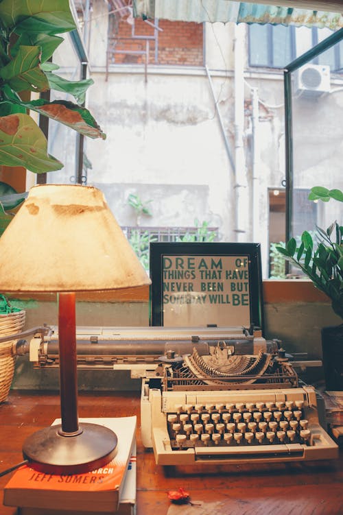 Белая пишущая машинка рядом с настольной лампой