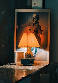 A warm, nostalgic scene featuring a lit lamp casting light on a vintage poster in a cozy room setting.
