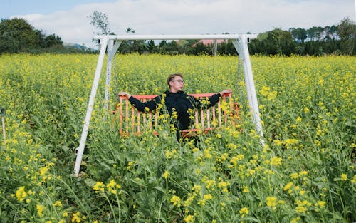 Man Sitting on White and Orange Swing Bench