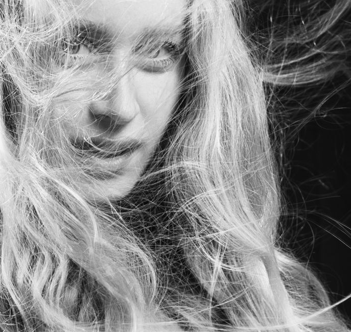 Captivating black and white studio portrait of a woman with flowing blonde hair, expressing emotion and movement.