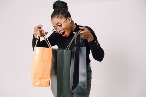 Free A smiling woman with eyeglasses happily admires her shopping bags against a white background. Stock Photo