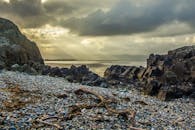 日出时分，宁静的岩石海滩上，戏剧性的阳光冲破云层