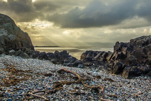 日出时分，宁静的岩石海滩上，戏剧性的阳光冲破云层