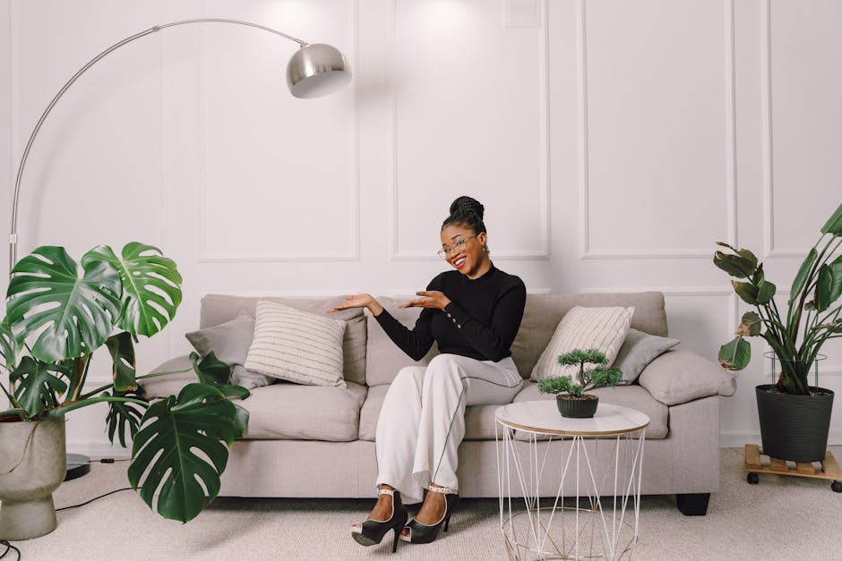 Chic modern living room with a smiling woman on the couch, surrounded by plants and decor.
