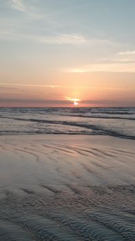 Peaceful beach sunset with serene waves and a colorful sky.