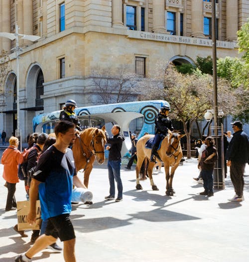 People walking on the street with horses and police