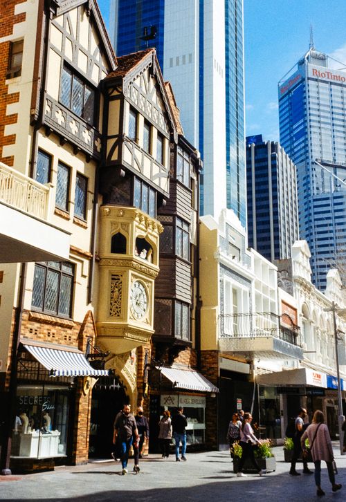 Free A vibrant street scene in Perth featuring the historic London Court with towering modern skyscrapers in the background. Stock Photo