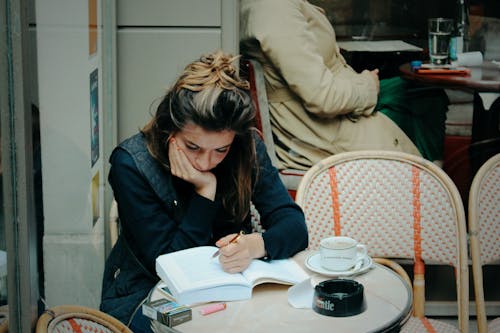 Woman Sitting with Book at Cafe
