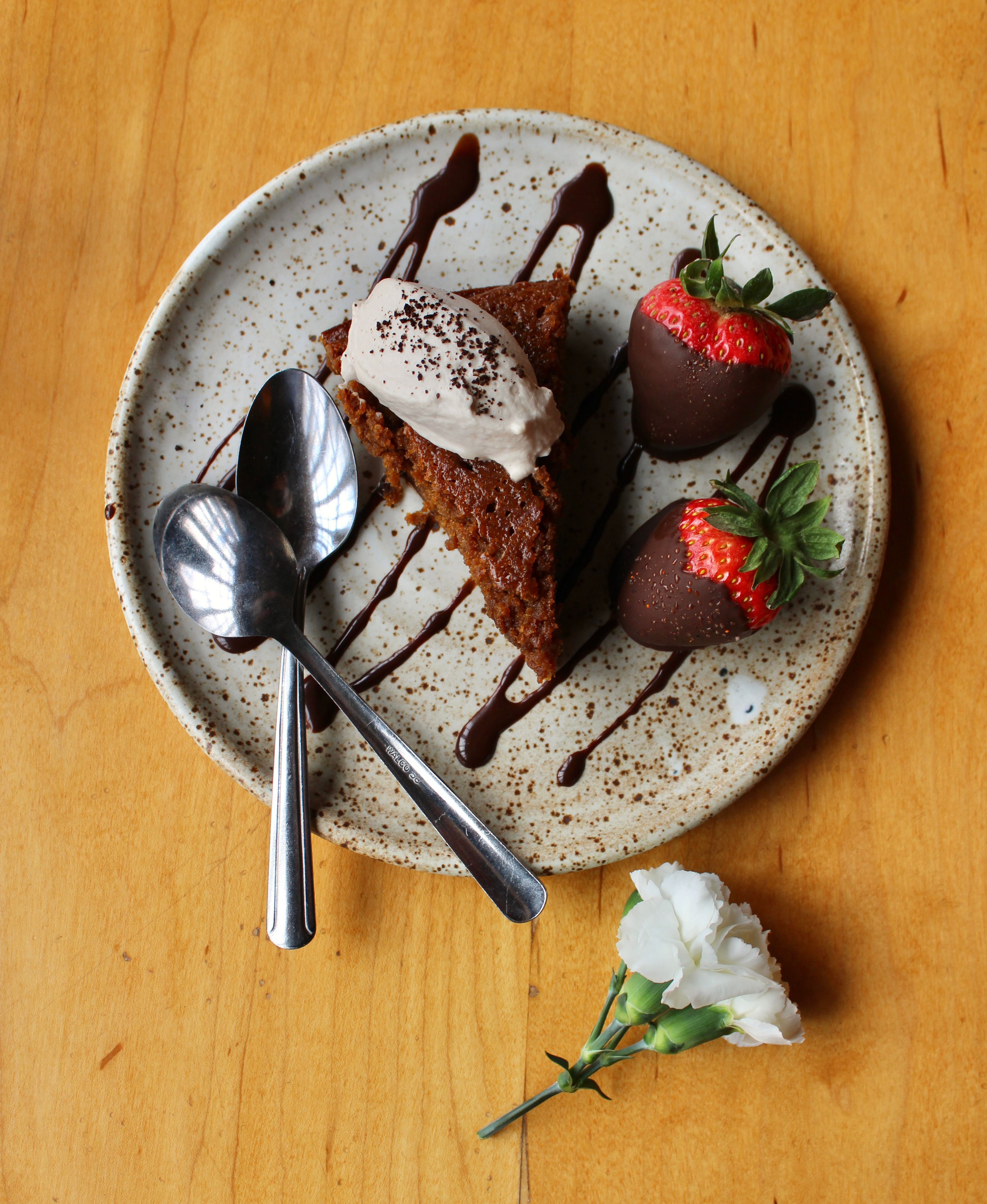 Slice of cake with chocolate sauce and strawberries on a plate, perfect for dessert lovers.