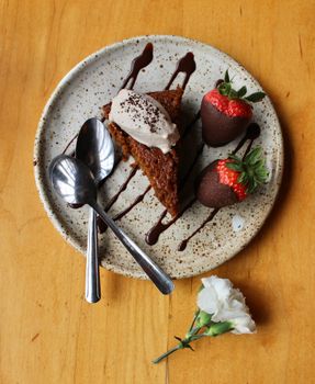 Slice of cake with chocolate sauce and strawberries on a plate, perfect for dessert lovers.