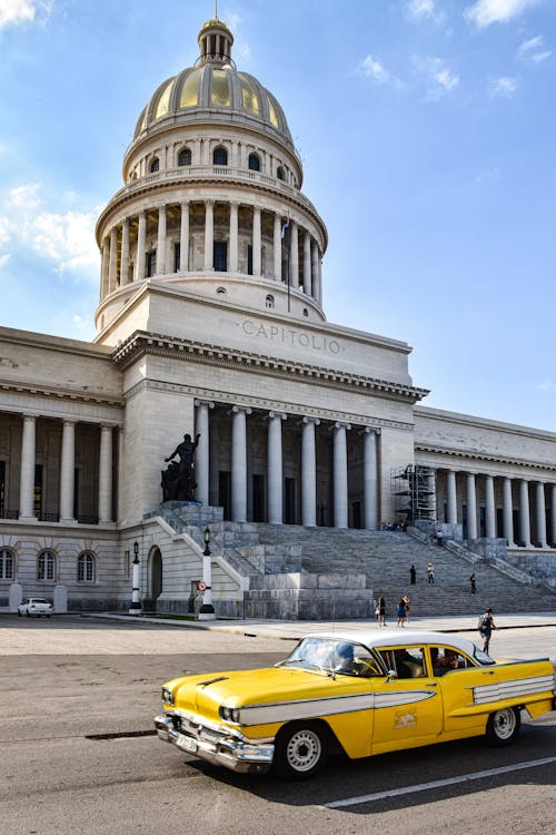 Free A Vintage Yellow Car in front of the National Capitol of Cuba Stock Photo