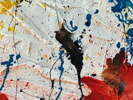 Close-up of colorful abstract paint splatters in an expressionist style on a textured surface.