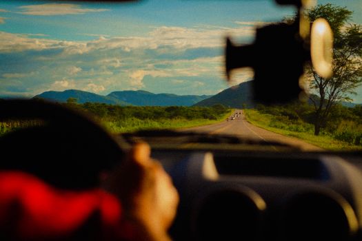 View through a car windshield of a road in Sobral, Brazil, surrounded by mountains and lush greenery.