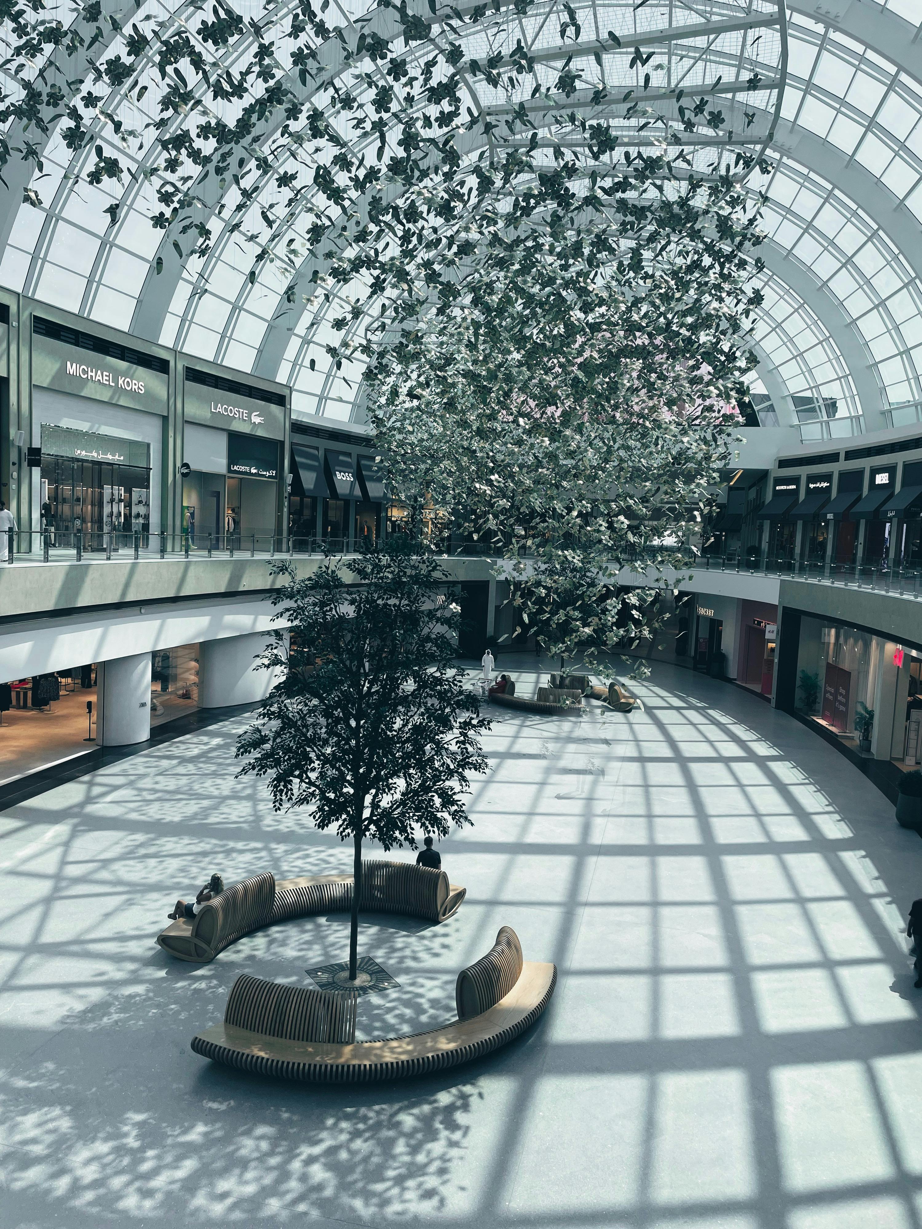 Spacious mall atrium with glass ceiling and artistic hanging installation.