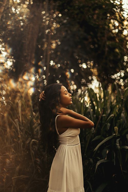 Free Portrait of a woman in a white dress amidst lush greenery, exuding grace and tranquility. Stock Photo