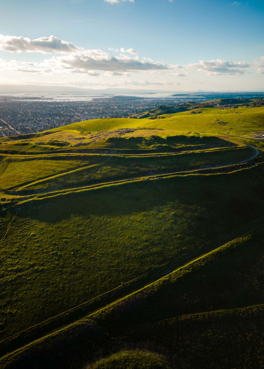 Aerial view of rolling green hills above a coastal valley — photo by Nathan Tran on Pexels