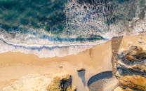 令人惊叹的海滩鸟瞰图，阳光下有汹涌的海浪、沙质海岸和岩石结构