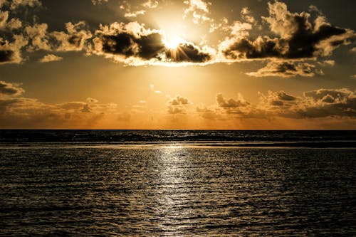 無料 海の上の雲に覆われた太陽 写真素材