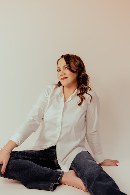 Brunette Woman in White Shirt Sitting on Floor in Studio