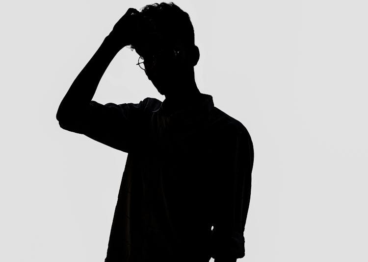 Silhouette Of Standing Man With Hand On Head