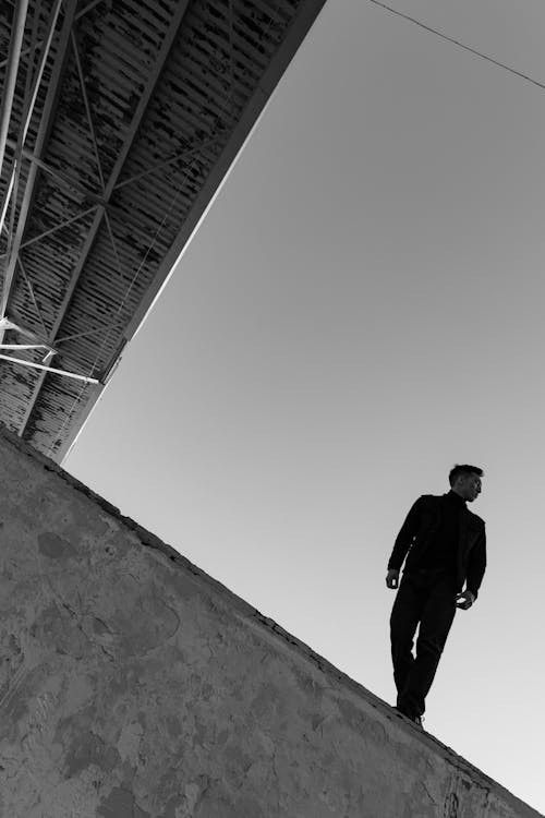 Low Angle Shot of a Man Standing on a Building Rooftop 