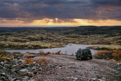 Car on Dirt Road by Lake