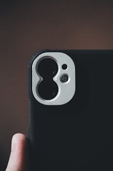 A detailed close-up of a smartphone camera lens against a subtle brown background.