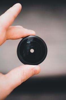 Detailed view of a hand holding a lens element, emphasizing optics and technology.