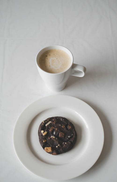 Free Mug of Cappuccino and a Chocolate Cookie on a Plate Stock Photo