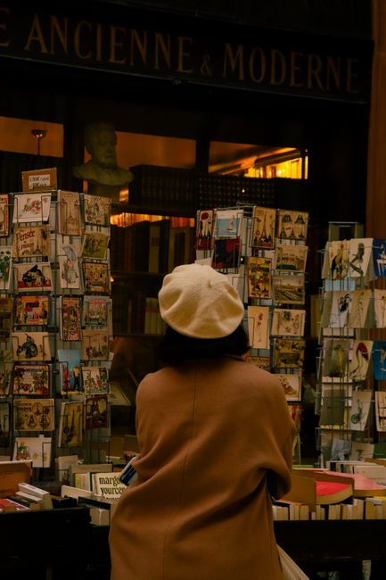 A woman browsing postcards at a classic Parisian bookstore, exuding vintage charm.