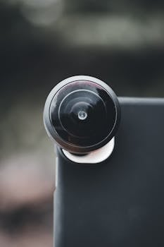 Detailed view of a fisheye lens attached to a smartphone, showcasing modern mobile photography.
